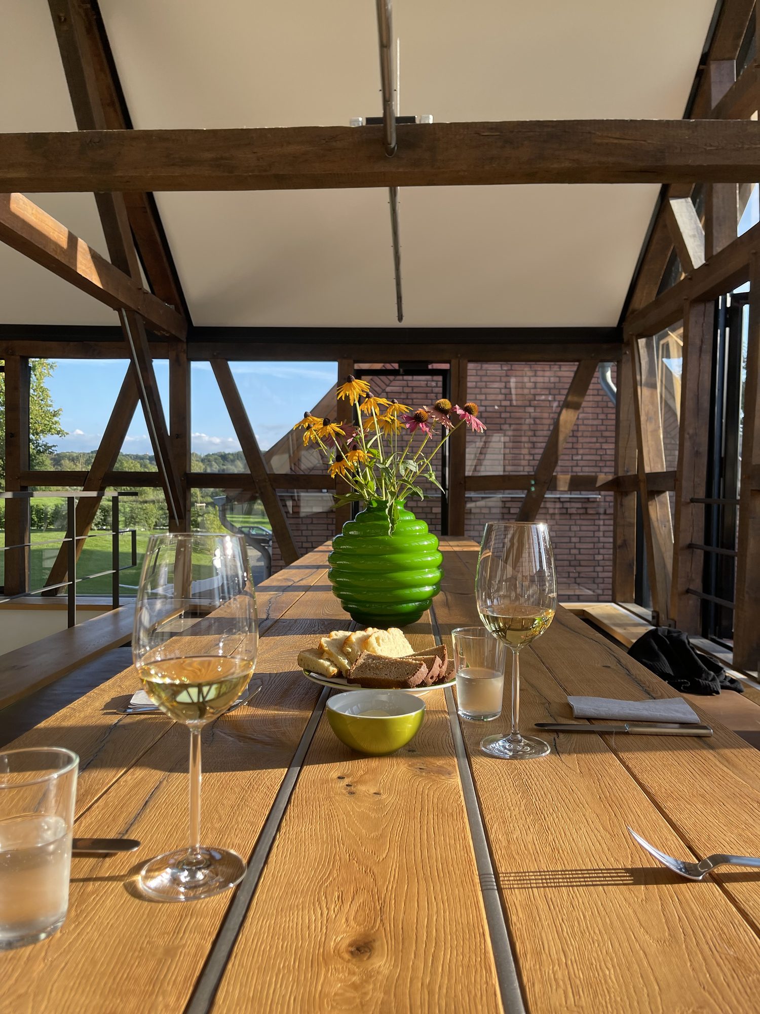 Gedeckte Tafel mit Weingläsern, Brot und Blick über die Landschaft im Abendlicht